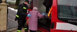 Na zdjęciu druh OSP w Ruszelczycach pomaga starszej osobie podczas wsiadania do samochodu OSP w celu transportu do punktu szczepień