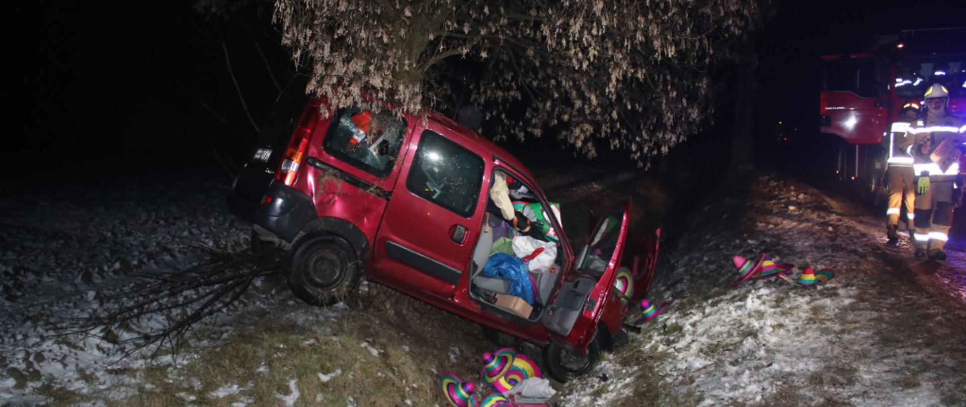 Zdjęcia przedstawia samochód osobowy po uderzeniu w drzewo, leżący w rowie.