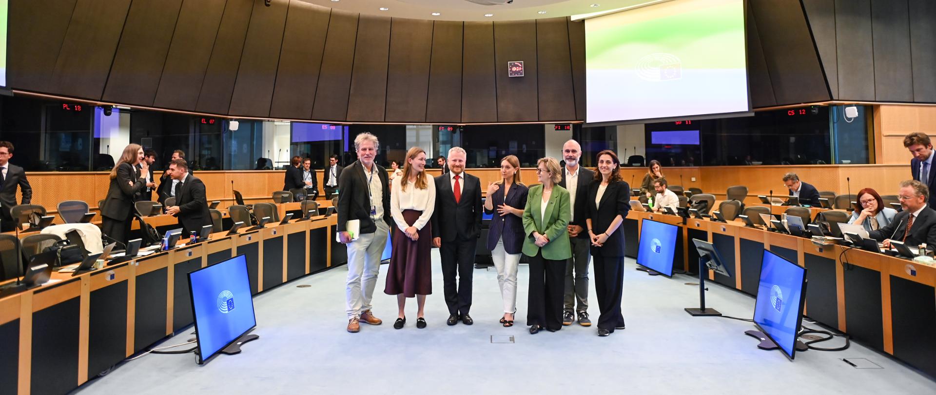 Uczestnicy spotkania stoją na sali obrad