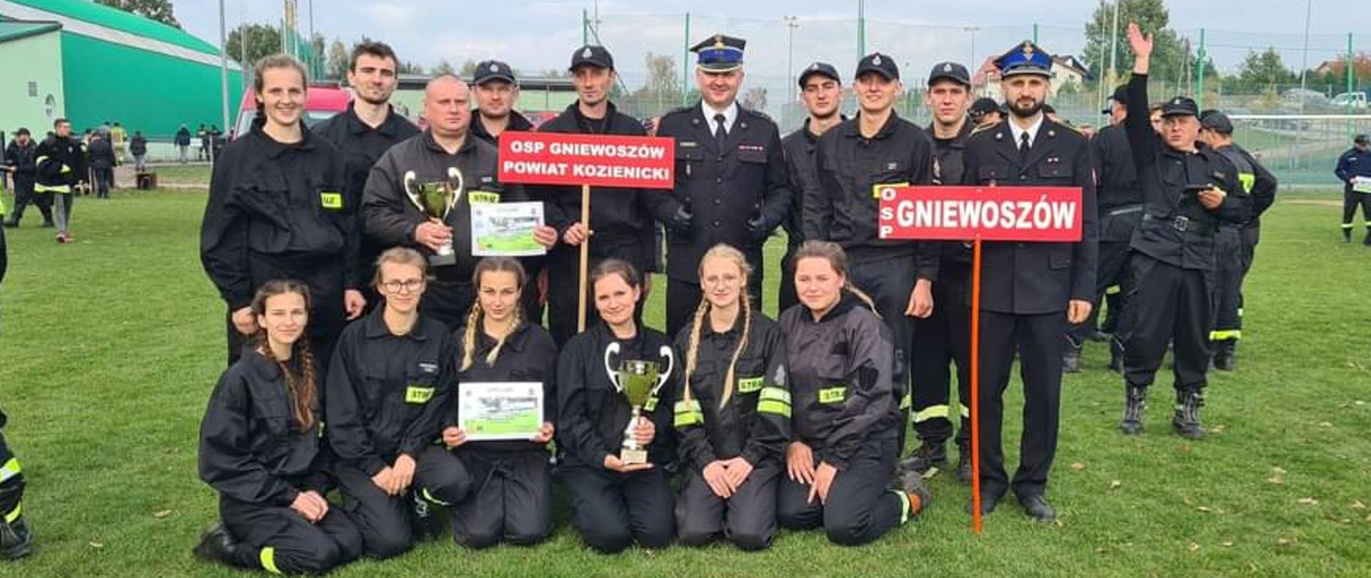drużyny OSP Gniewoszów z Komendantek Powiatowym PSP w Kozienicach pozują do zdjęcia grupowego na stadionie trawiastym