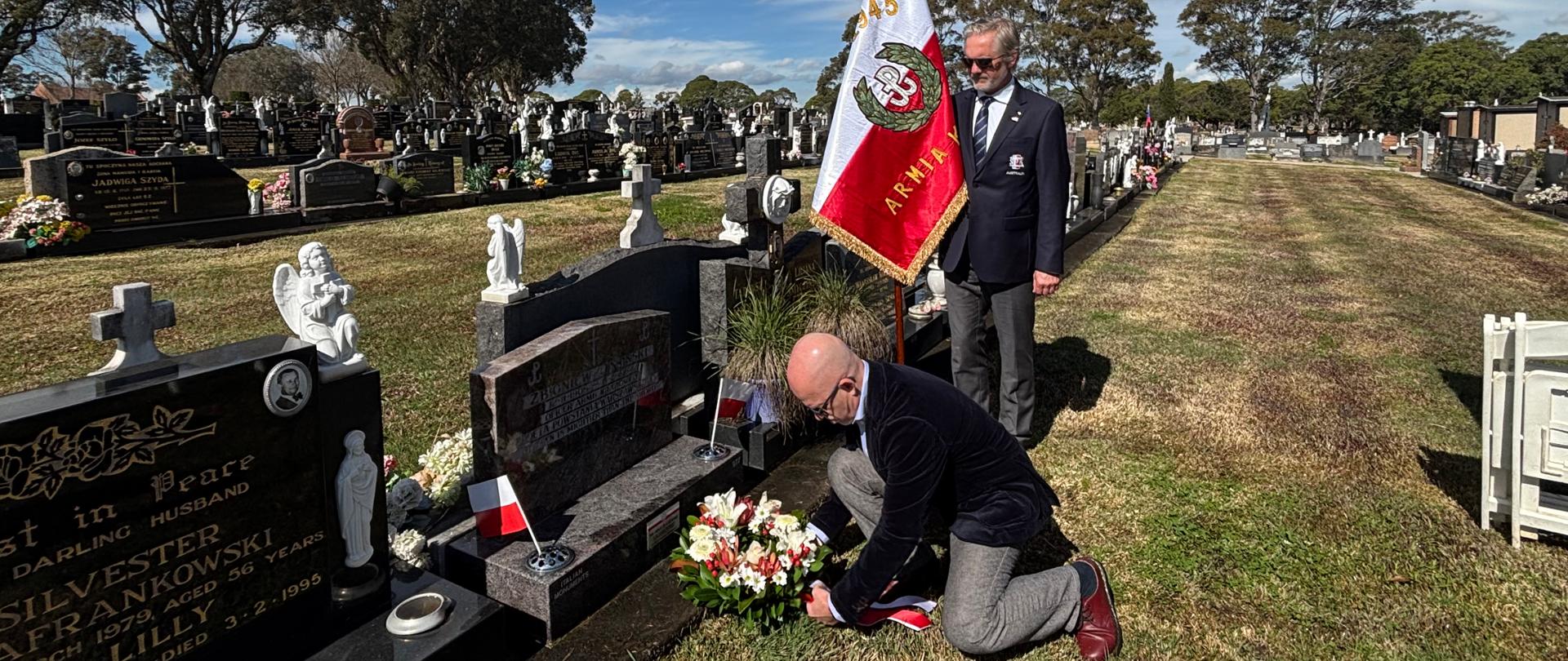 The Consul General kneels to lay flowers on Zbigniew Jasiński's grave.
