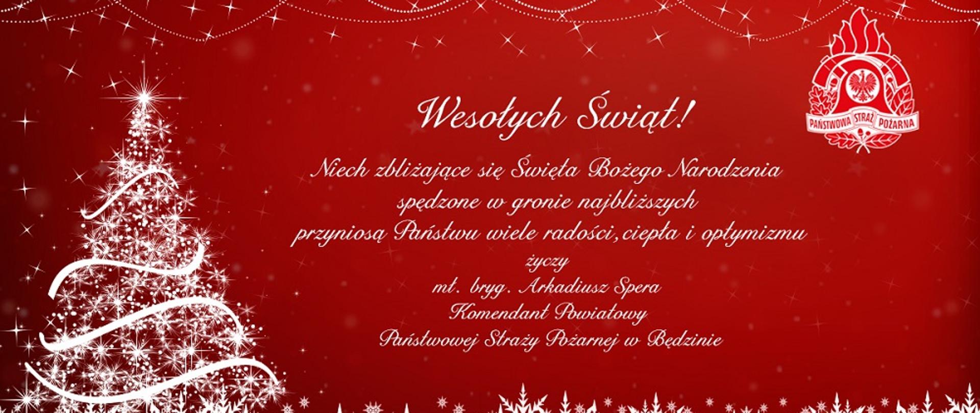 Zdjęcie w formie kartki pocztowej na czerwonym tle przedstawia po lewej stronie białą choinkę. W górnym prawym roku znajduje się logo Państwowej Straży Pożarnej. W środkowej części zdjęcia znajduje się duży napis białymi literami Wesołych Świąt. Po napisem również białymi literami opisane są życzenia świąteczne Komendanta Powiatowego Państwowej Straży Pożarnej w Będzinie mł. bryg. Arkadiusz Spera. Całość kartki zdobią białe gwiazdki i płatki śniegu.