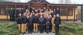 Zdjęcie grupowe, uczestnicy narady stoją na dworze przed budynkiem pozując do zdjęcia