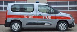 Nowy samochód specjalny. Plac Komendy Powiatowej PSP w Rawiczu, na którym zaparkowany jest nowy nabytek - lekki samochód kwatermistrzowski. Auto ma srebrny kolor. Na karoserii naklejony jest czerwony pas, na którym znajduje się napis STRAŻ oraz numer 571P81. Widok z boku od strony pasażera.