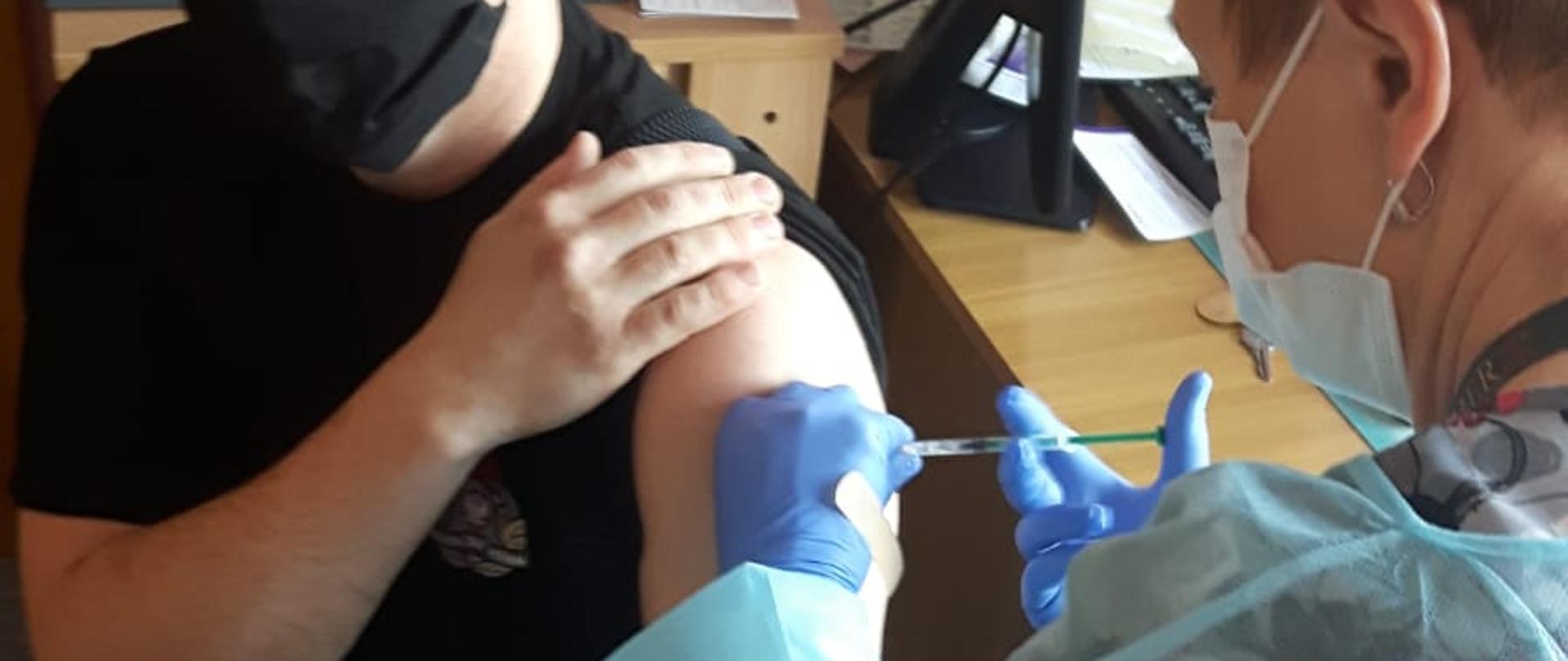 Na zdjęciu widać strażaka podczas szczepienia przeciwko COVID-19