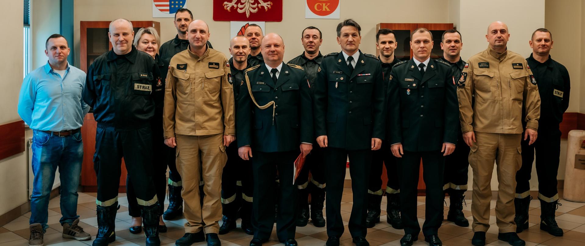 Pamiątkowe zdjęcie: w kadrze umieszczono ratowników z Jednostki Ratowniczo-Gaśniczej nr 3 w Kielcach. W pierwszym rzędzie stoją: Komendant Miejski PSP, dowódca JRG Nr 3 w Kielcach, zastępca dowódcy JRG Nr 3, naczelnik Wydziału Organizacyjno-Kadrowego KM PSP oraz odchodzący funkcjonariusz st. ogn. Marcin Milcarz