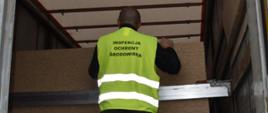 Inspektor Ochrony Środowiska kontrolujący zawartość naczepy ciężarówki.