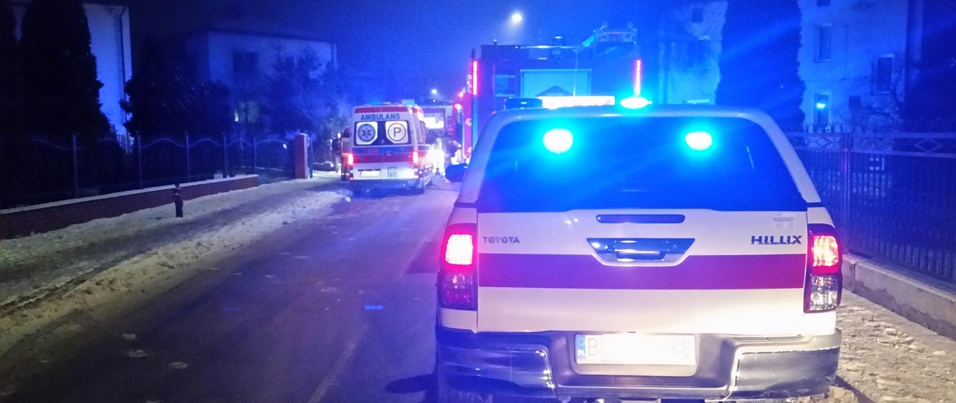 Pojazdy służb ratowniczych stoją na ulicy.