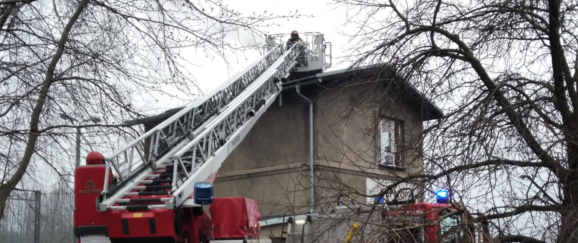 Widoczne miejsce zdarzenia oraz strażacy działający na dachu budynku.