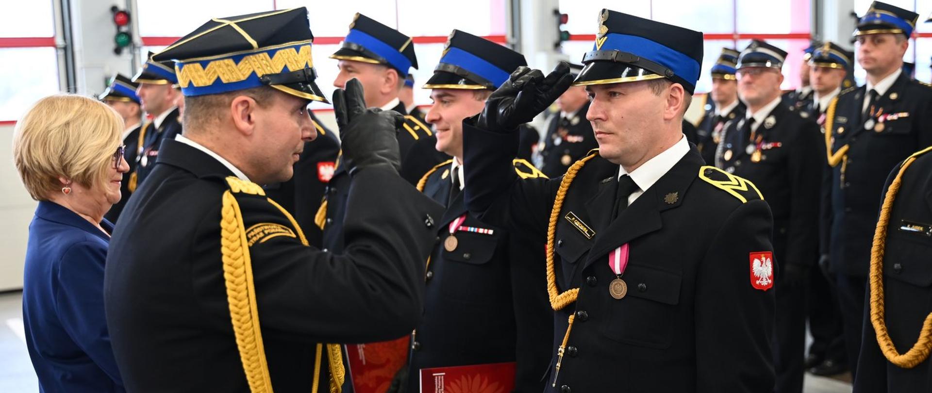 Strażak PSP otrzymuje salut i odznaczenie podczas uroczystości związanej z Narodowym Świętem Niepodległości w JRG 3 w Rzeszowie.