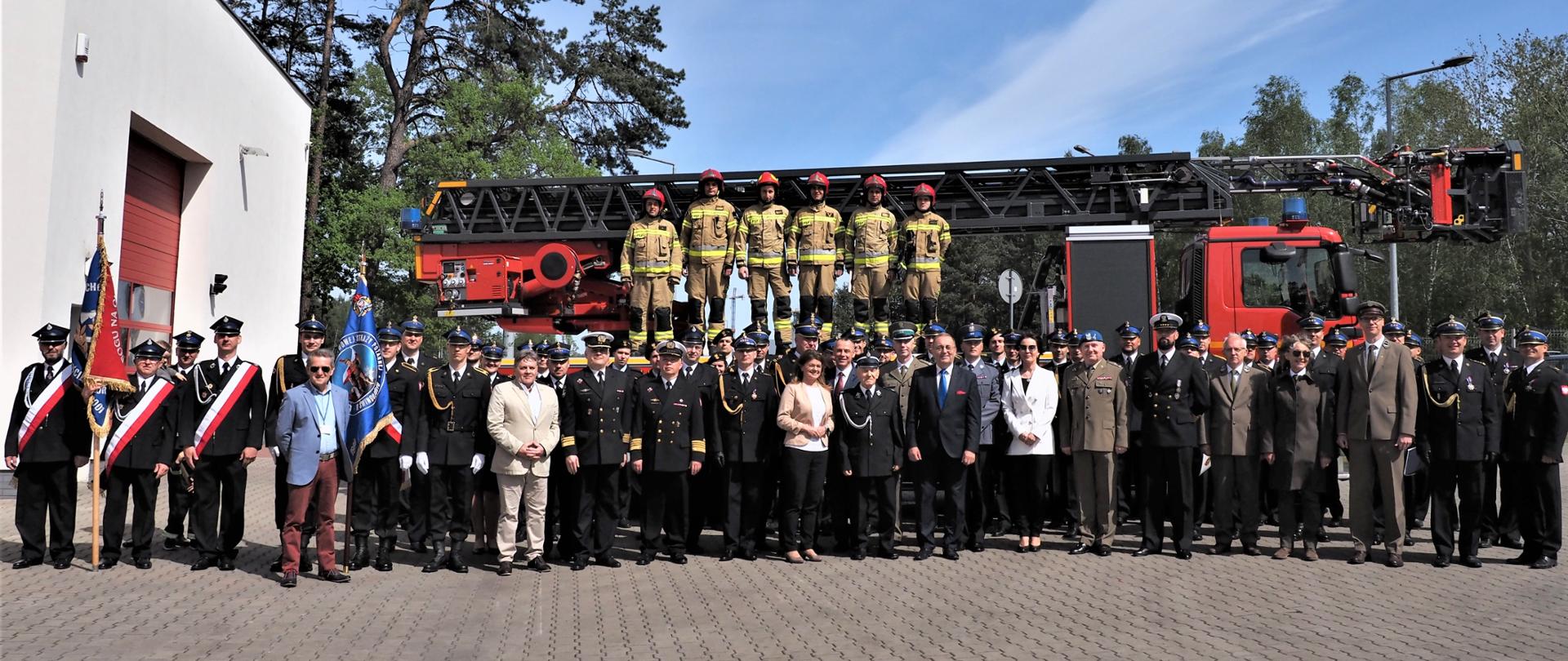 Zdjęcie wspólne uczestników uroczystości na tle drabiny mechanicznej.
