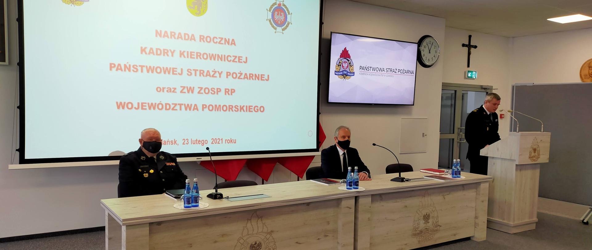 na zdjęciu przy biurku oraz mównicy widoczni od prawej: Pomorski Komendant Wojewódzki Państwowej Straży Pożarnej starszy brygadier Piotr Socha, Wojewoda Pomorski Dariusz Drelich oraz przedstawiciel Oddziału Wojewódzkiego Związku Ochotniczych Straży Pożarnych województwa pomorskiego.