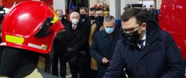 Widok z boku. Wojewoda małopolski w momencie wręczania dowódcy JRG Andrychów kluczyków do nowego samochodu ratowniczo-gaśniczego. Po lewej stronie widoczni zaproszeni goście.