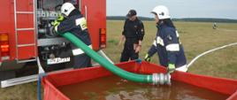 Ćwiczenia "Plutonu Rawicz". Teren nad zbiornikiem retencyjnym w Jutrosinie. Do zbiornika przenośnego o pojemności 2 500 litrów strażacy z OSP w Szkaradowie wkładają linię ssawną, aby za pomocą autopompy zassać wodę, a następnie tłoczyć ją w kierunku pożaru. 