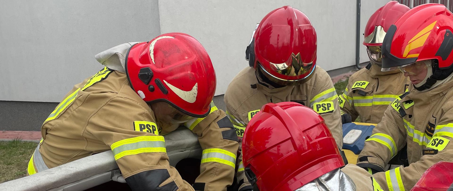 Na zdjęciu strażacy ewakuują poszkodowanego z pojazdu osobowego za pomocą noszy typu deska.