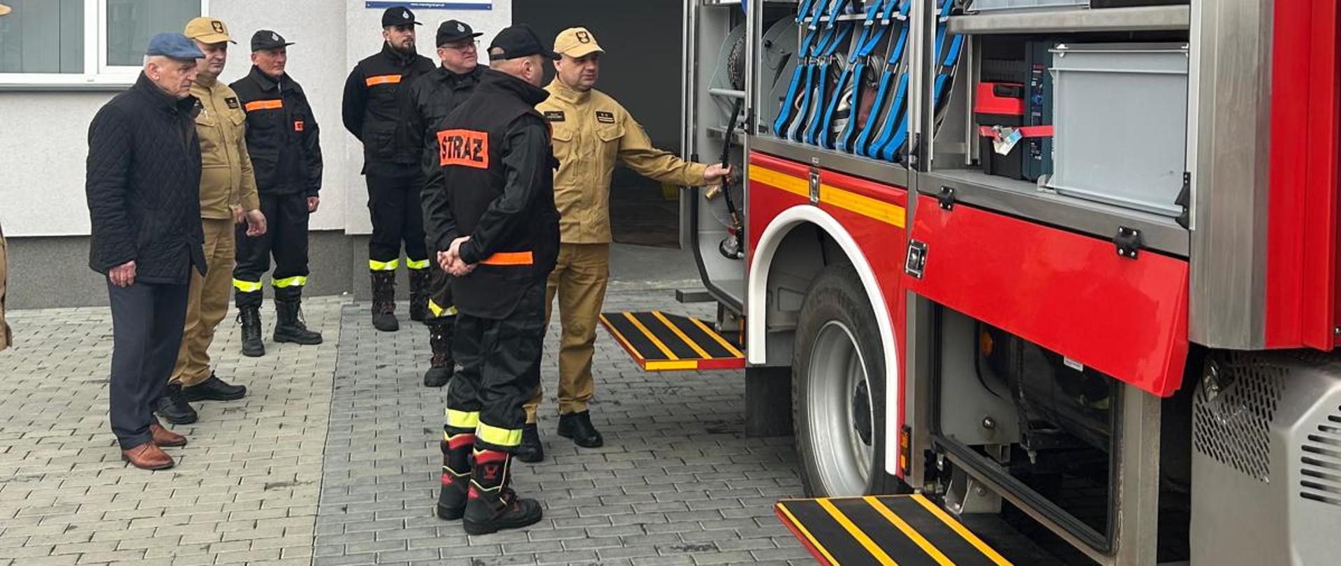 Komendanci oraz druhowie OSP przed remizą OSP przy pojeździe ratowniczym