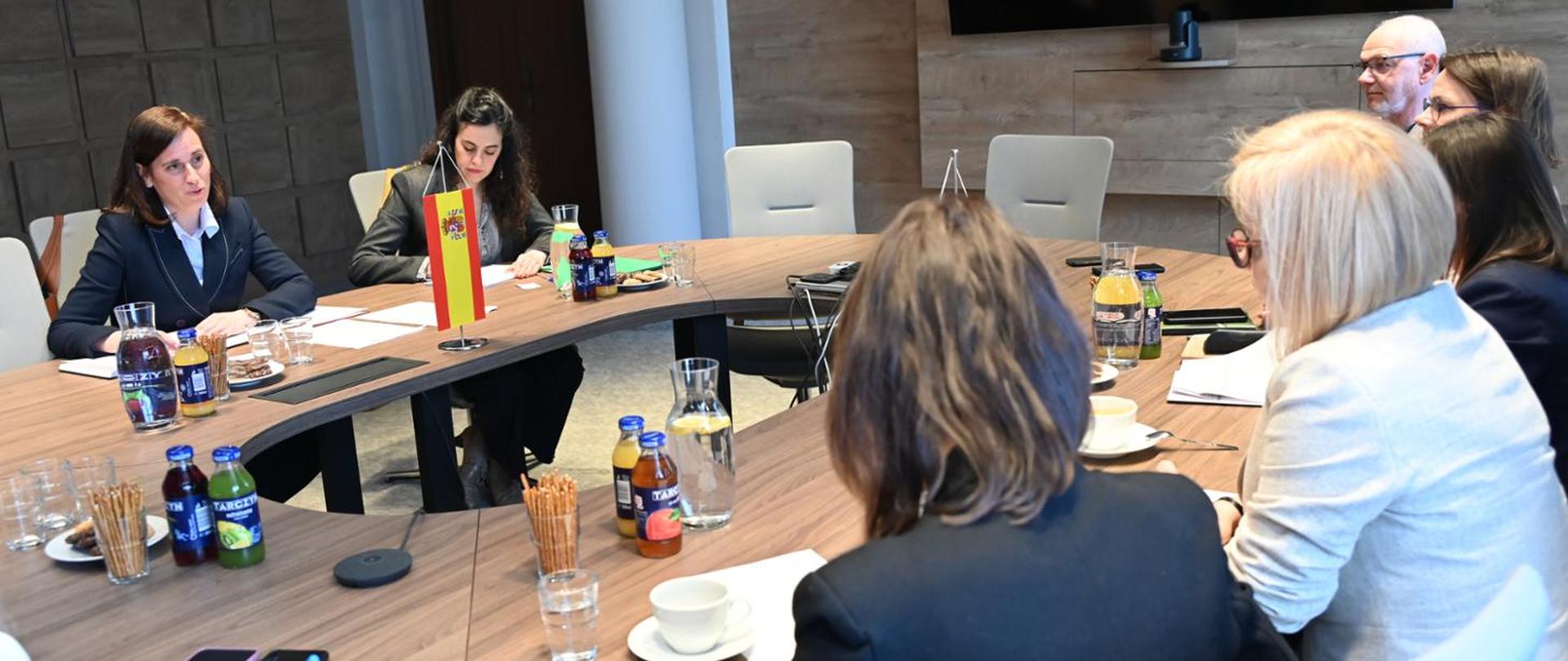 Meeting of the Minister of Climate and Environment, Paulina Hennig-Kloska, with the newly appointed Ambassador of the Kingdom of Spain, Victoria Ortega Gutiérrez. In the photo, the two women are seated opposite each other at a round table, engaged in conversation. Five additional participants are also visible at the table, and the meeting takes place in a conference room.