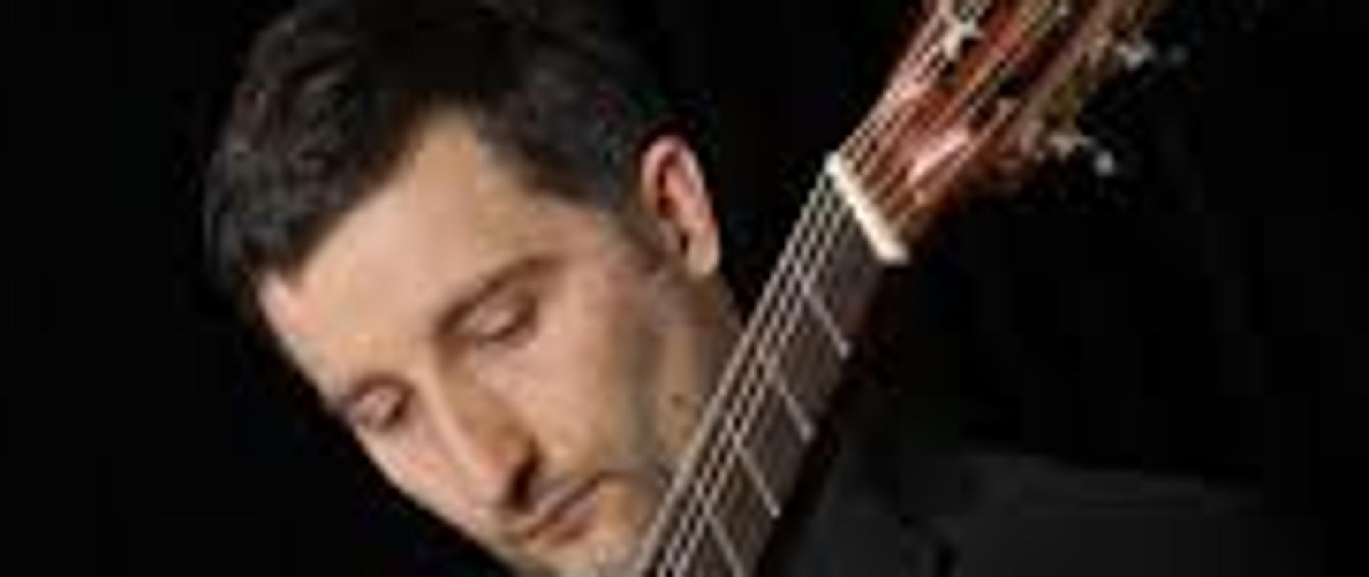 Na zdjeciu Waldemar Gramolak trzymajacy gitarę 