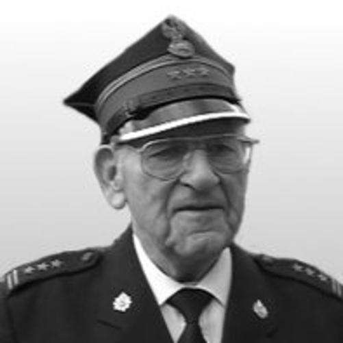 czarno-białe zdjęcie strażaka w okularach w mundurze i rogatywce, w białej koszuli z krawatem