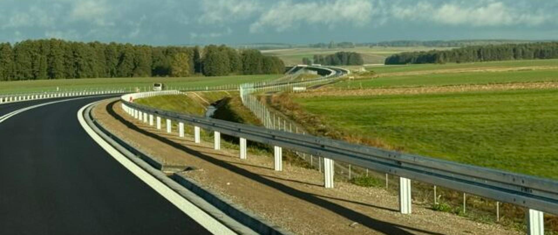 Autostrada z mostem na pierwszym planie, w tle rozciąga się pole.