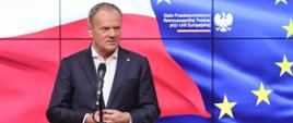 Premier Donald Tusk podczas konferencji prasowej w Stałym Przedstawicielstwie RP przy Unii Europejskiej, 21.03.2025. W tle ekran z flagami Polski i Unii Europejskiej.