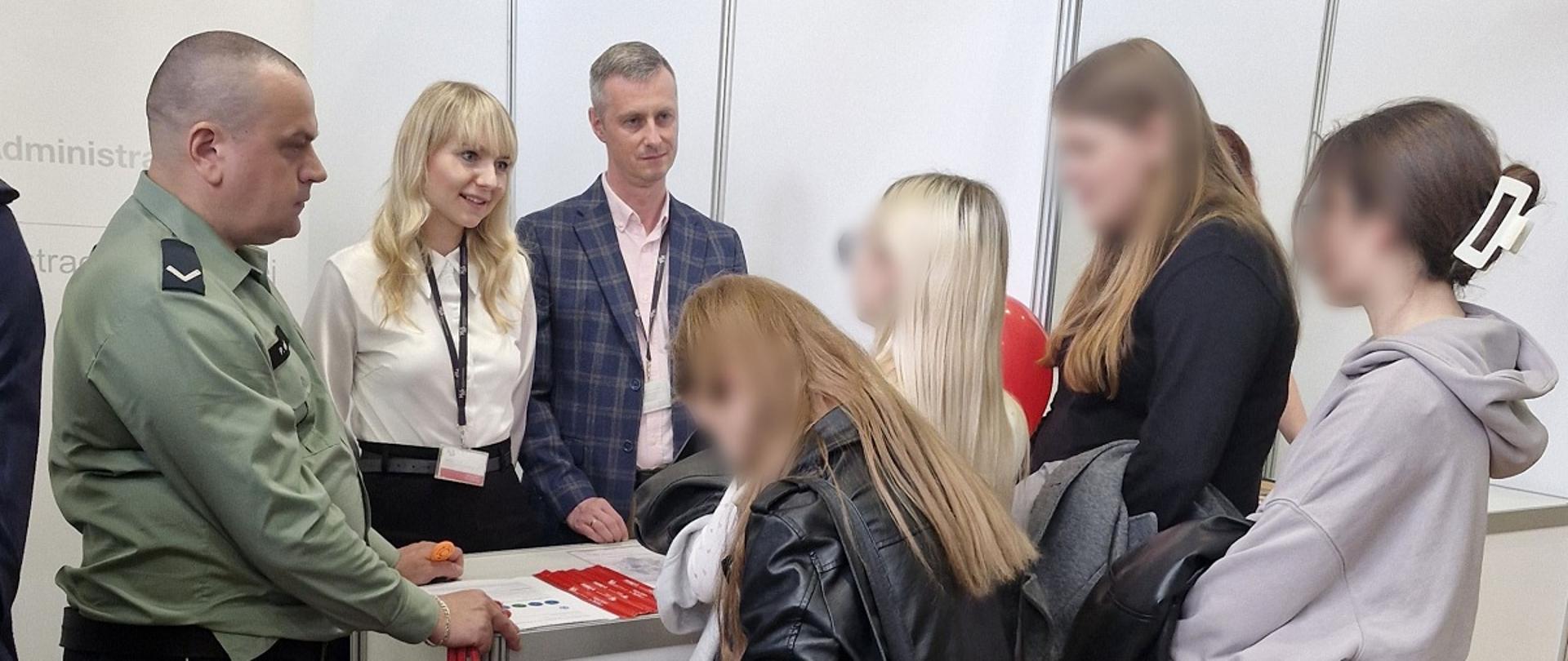 Stanowisko podkarpackiej KAS na targach pracy. Funkcjonariusz SCS i pracownicy KAS rozmawiają z młodzieżą. 