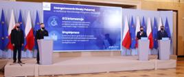Komendant Główny PSP wraz z przedstawicielami rządu przy mównicach na tle banneru Narodowego Programu Szczepień.