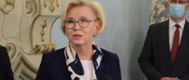 Wiceminister Marzena Machałek z wizytą w Zespole Szkół w Biedrzychowicach przemawia do mikrofonu. 