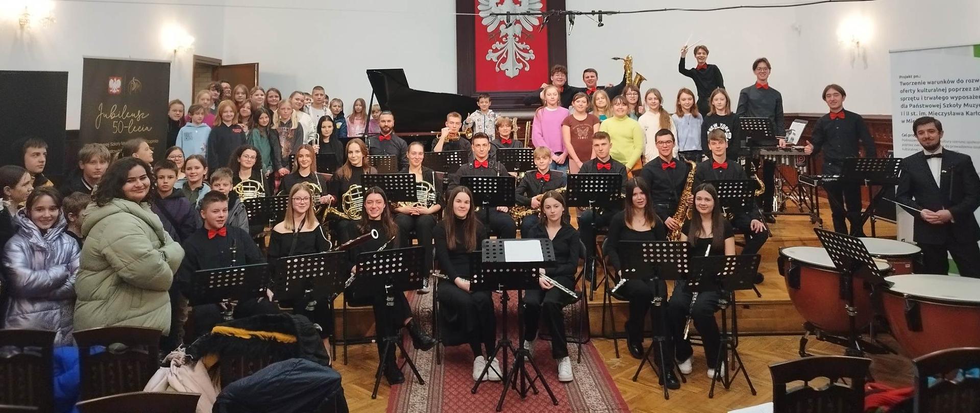 orkiestra dęta PSM II stopnia oraz uczestnicy pierwszego z koncertów informacyjno-edukacyjny dla kandydatów do PSM I stopnia zgromadzeni na scenie Sali Królewskiej PSM w MIelcu