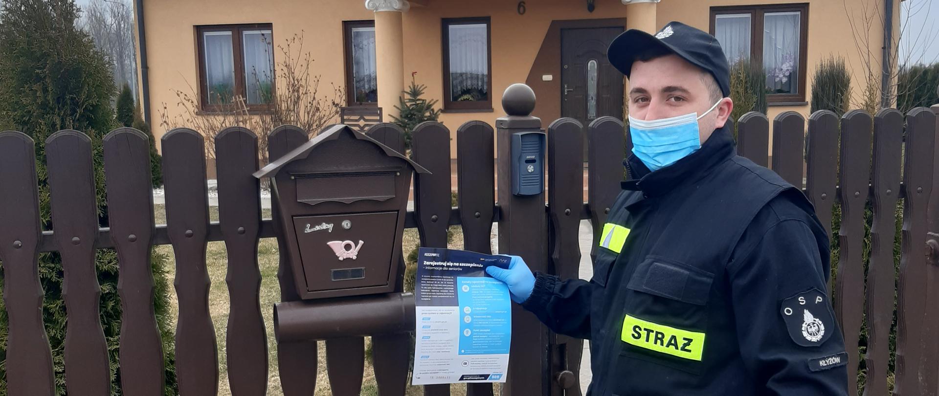 Druh OSP umieszcza ulotkę informacyjną w skrzynce pocztowej na jednej z posesji