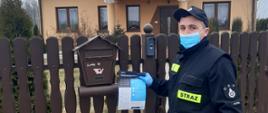 Druh OSP umieszcza ulotkę informacyjną w skrzynce pocztowej na jednej z posesji