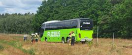 Autokar stoi na poboczu autostrady A2. Przy autobusie stoją strażacy oraz kilku pasażerów. 