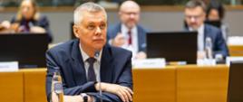 Minister Tomasz Siemoniak podczas posiedzenia Rady UE, przed ministrem mikrofon, szklanka, butelka wody i napis Polska. Za szefem MSWiA zasiada wiceminister Maciej Duszczyk oraz trzy pozostałe osoby. Tło jest rozmyte. 