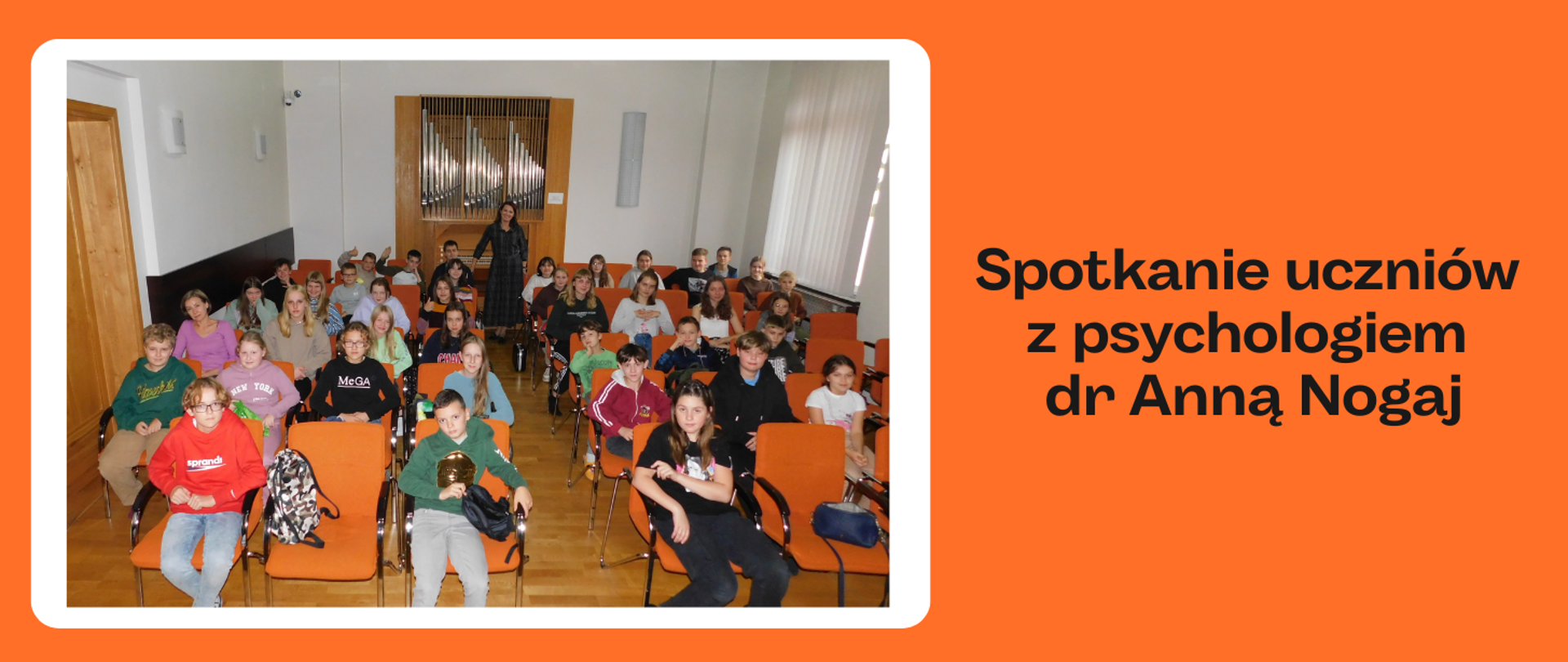 Na pomarańczowym tle z lewej strony w białej ramce zdjęcie. Na zdjęciu uczniowie siedzący na pomarańczowych fotelach. W tyle organy piszczałkowe, a przed nimi w ciemnej sukience stoi kobieta. Po prawej stronie obrazka czarny napis: "Spotkanie uczniów z psychologiem dr Anną Nogaj"