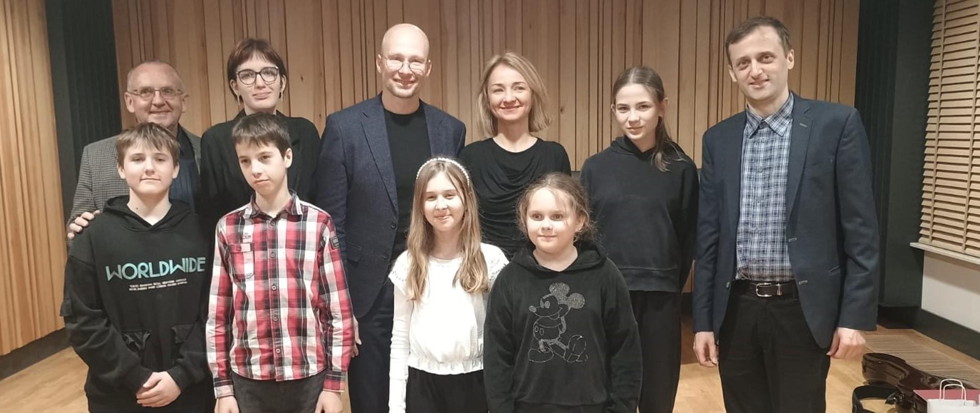 Grupa uczniów i nauczycieli na scenie sali koncertowej PSM