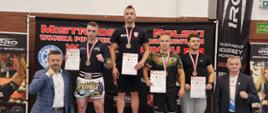 Zawodnicy stoją na podium z medalami. W tle baner z napisem Mistrzostwa Polski Wojska Polskiego i Służb Mundurowych w kickboxingu