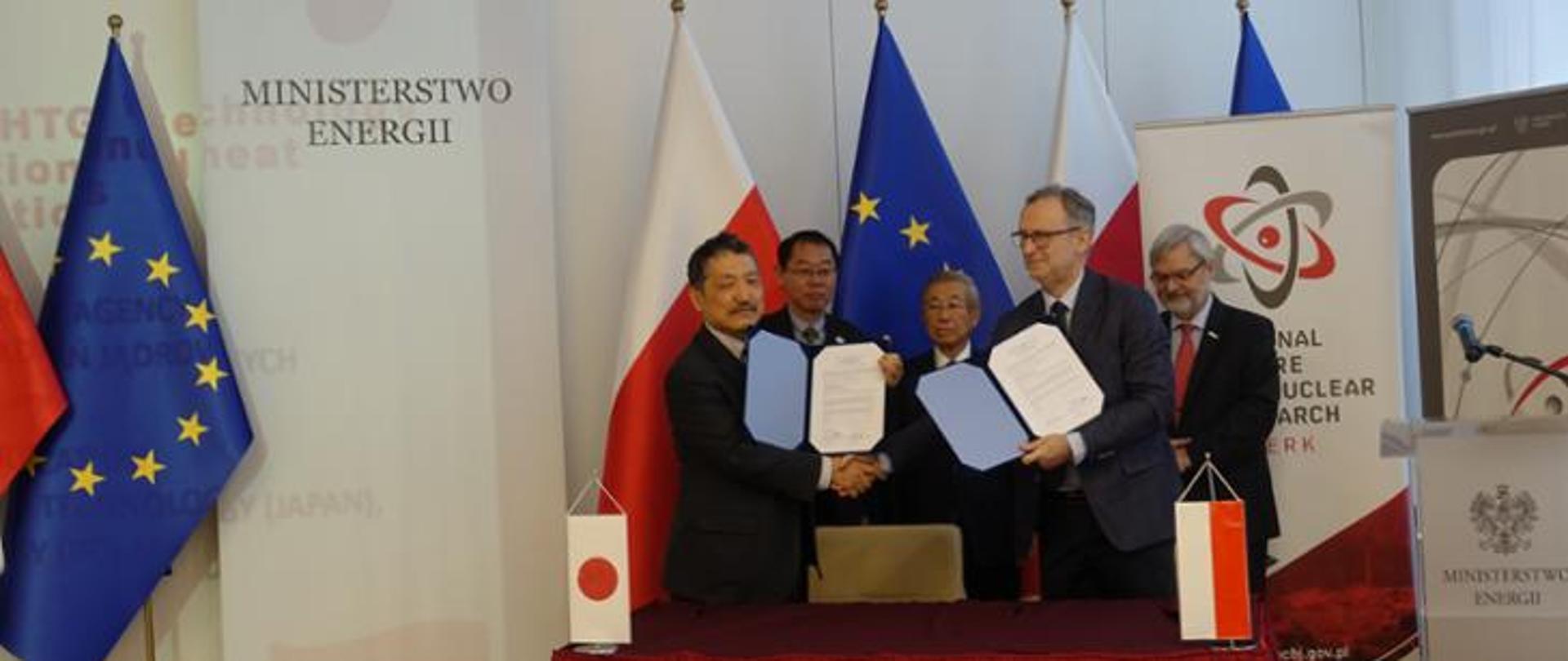 Zdjęcie przedstawiające przedstawicieli strony polskiej i japońskiej trzymających w rękach wydrukowane porozumienie o współpracy 