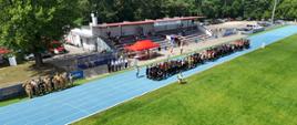 Powiatowe Zawody Sportowo-Pożarnicze, zawodnicy ustawieni na bieżni stadiony na zbiórce, podczas uroczystego rozpoczęcia zawodów, Goście oraz kibice 