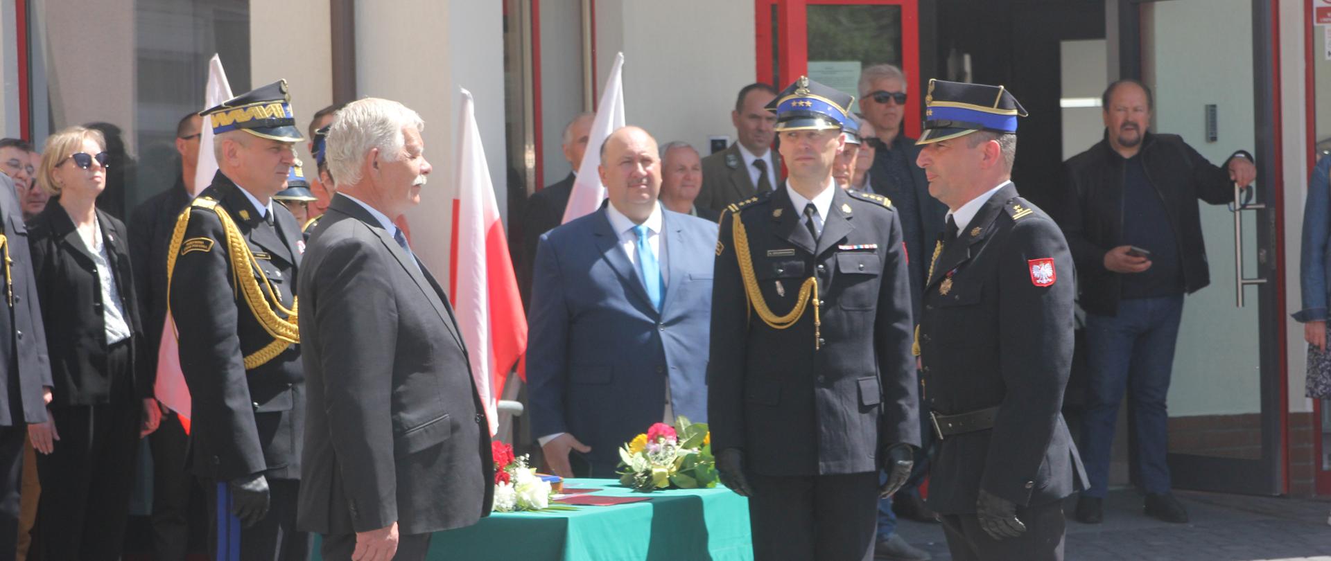 Na placu Komendy Powiatowej Państwowej Straży Pożarnej w Człuchowie Dowódca uroczystości brygadier Jan Kilkiewicz składa meldunek wicewojewodzie pomorskiemu Mariuszowi Łuczykowi. Obok soją: nadbrygadier Piotr Socha Pomorski Komendant Wojewódzki i st. bryg. Ernest Szczepański Komendant Powiatowy.