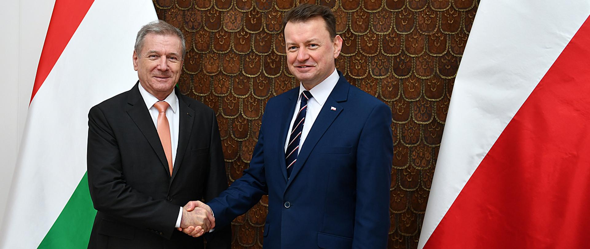 Przywitanie ministrów obrony Polski i Węgier na tle flag obu krajów