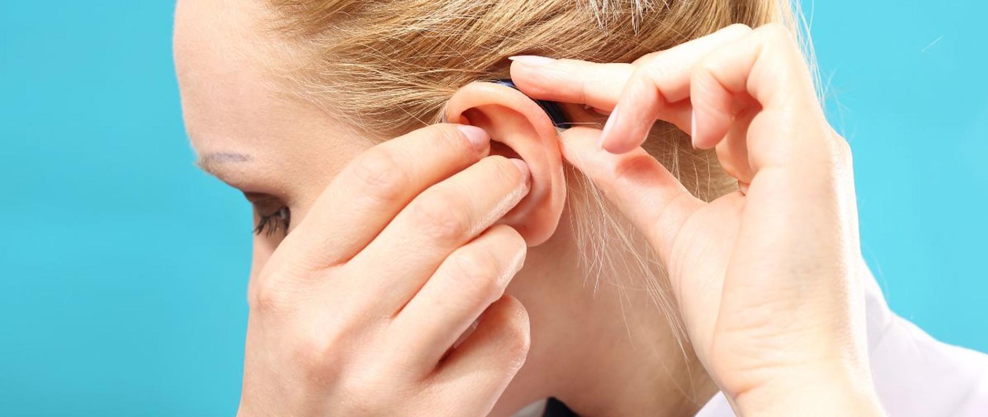 Pacjentka zakłada aparat słuchowy