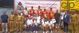 Grupowe zdjęcie zawodników i osób zaproszonych, za nimi napis Mistrzostwa Polski Strażaków PSP