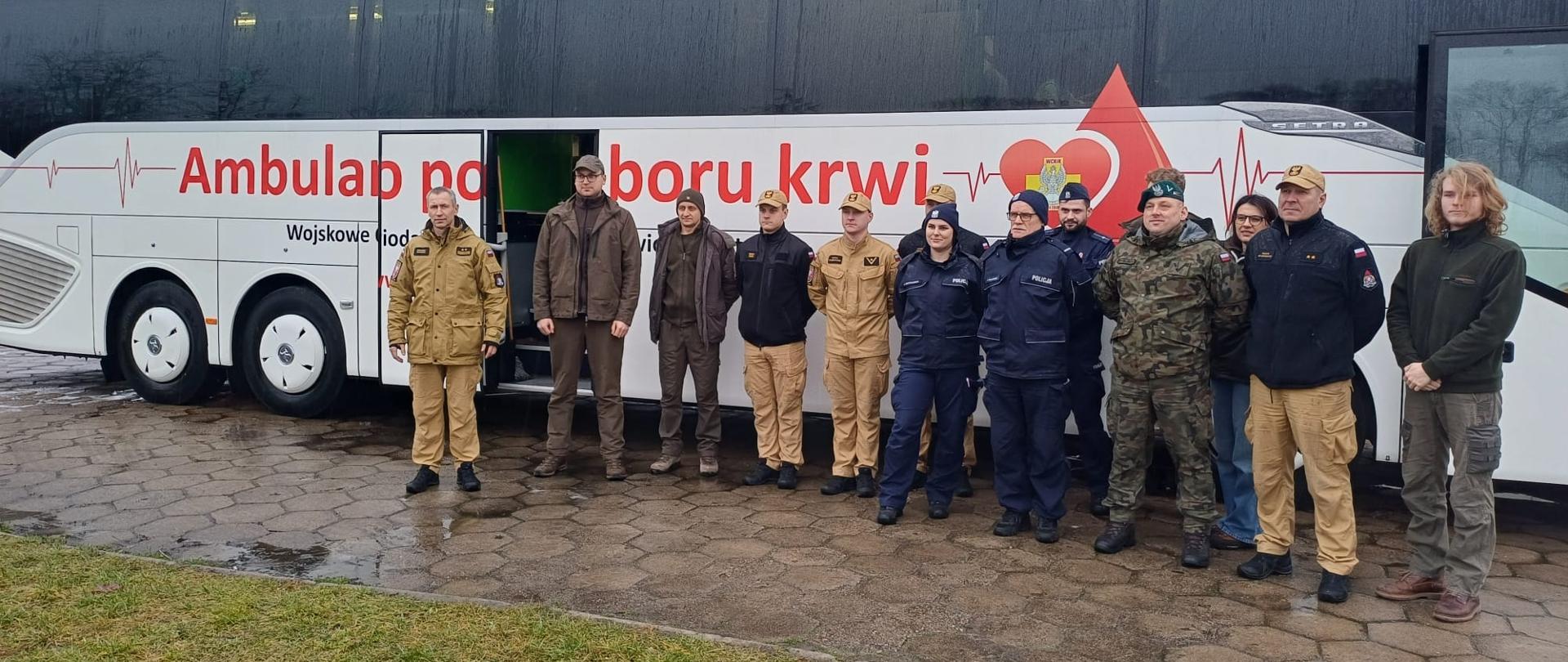 Wolontariusze stojący przed krwiobusem