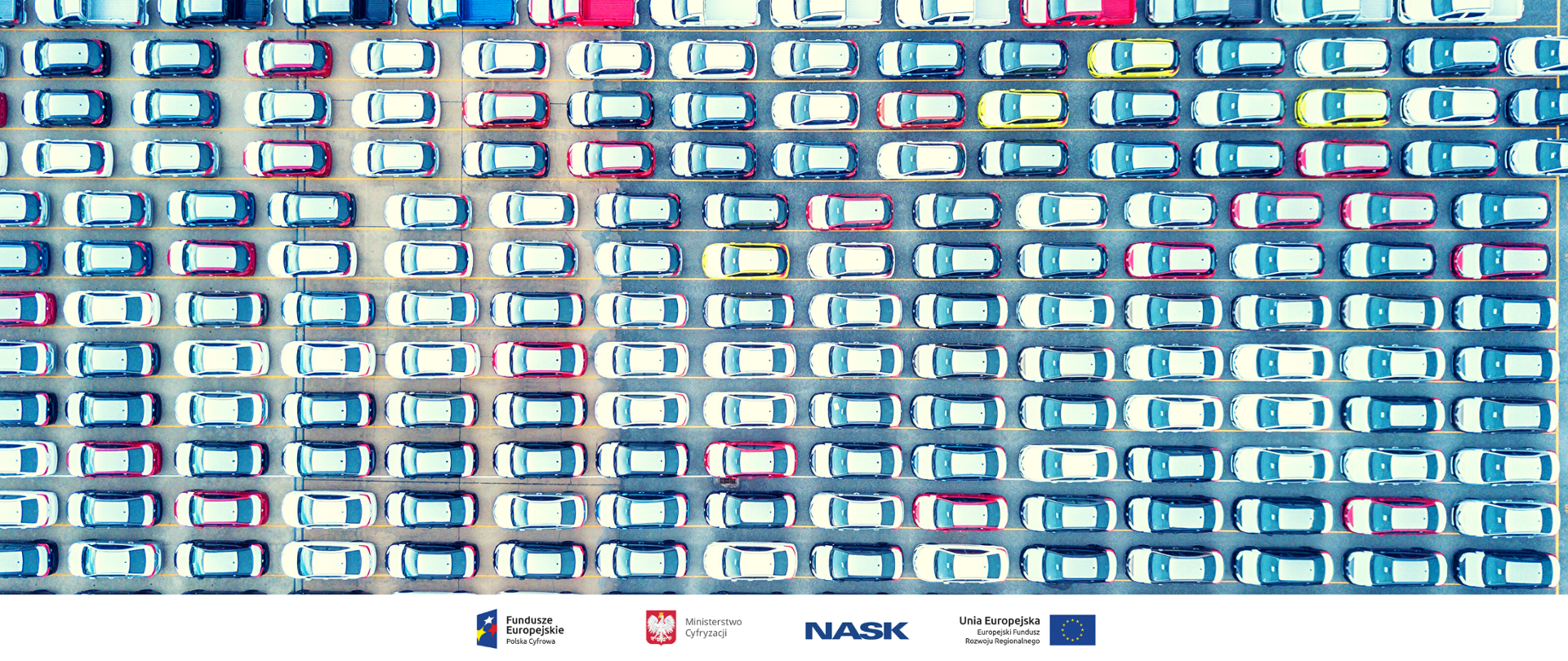 Parking widziany z góry. Kilkaset samochodów w równych rzędach.