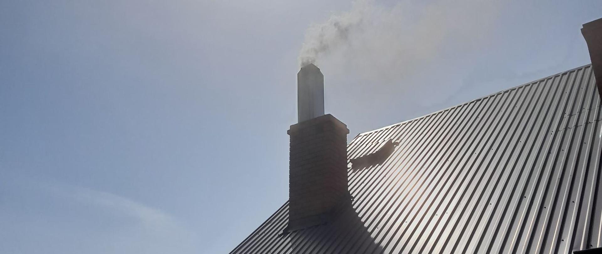 Zdjęcie przedstawia przewód dymowy, gdzie zapaliła się sadza. Widać kłęby ciemnego dymu wydobywającego się z komina