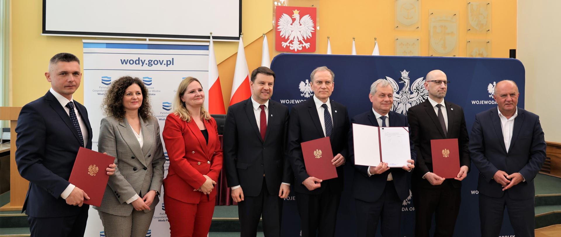 grupa ludzi stojąca na ściance reklamowej