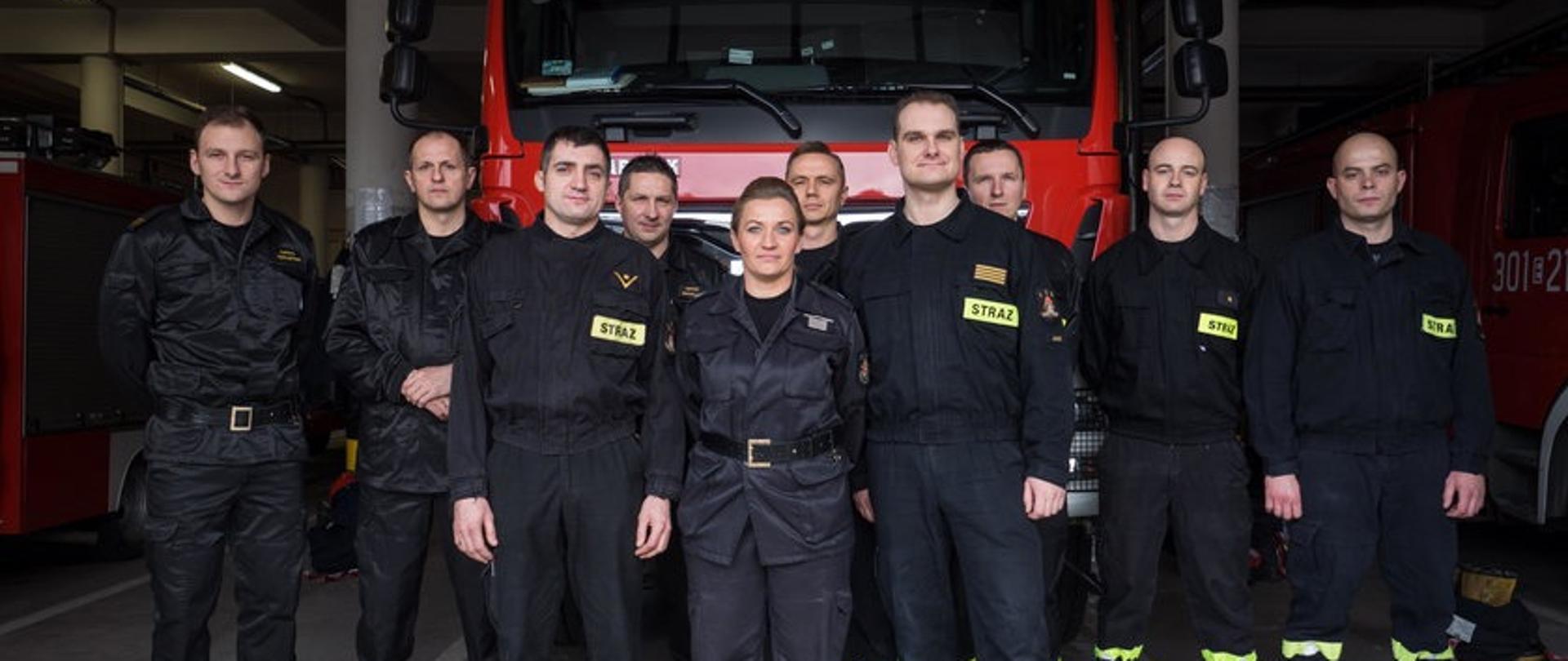 Na zdjęciu grupa strażaków w tle samochód ratowniczo-gaśniczy