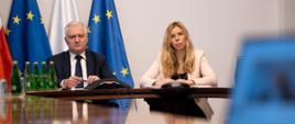Od lewej, za stołem konferencyjnym, siedzą Jarosław Gowin i Anna Kornecka. Za nimi flagi polska i unijna, przed nimi notatki i mikrofon.