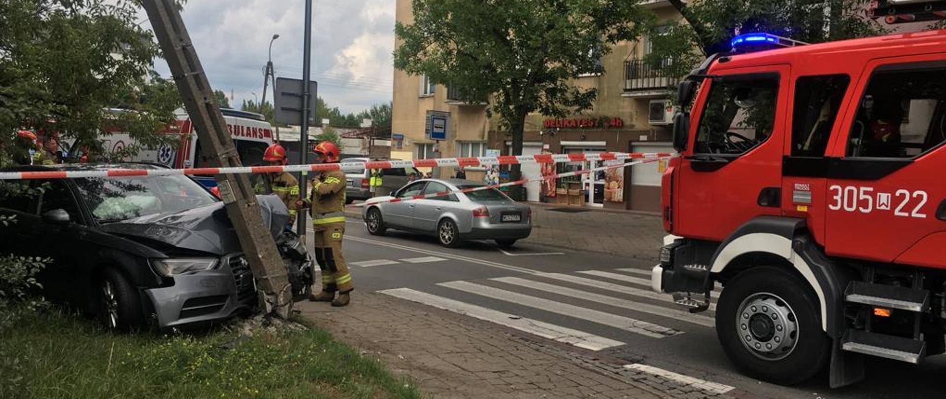 Samochód uderzył w słup, strażacy przy samochodzie stoją