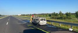 Samochód osobowy po pożarze oraz strażacy